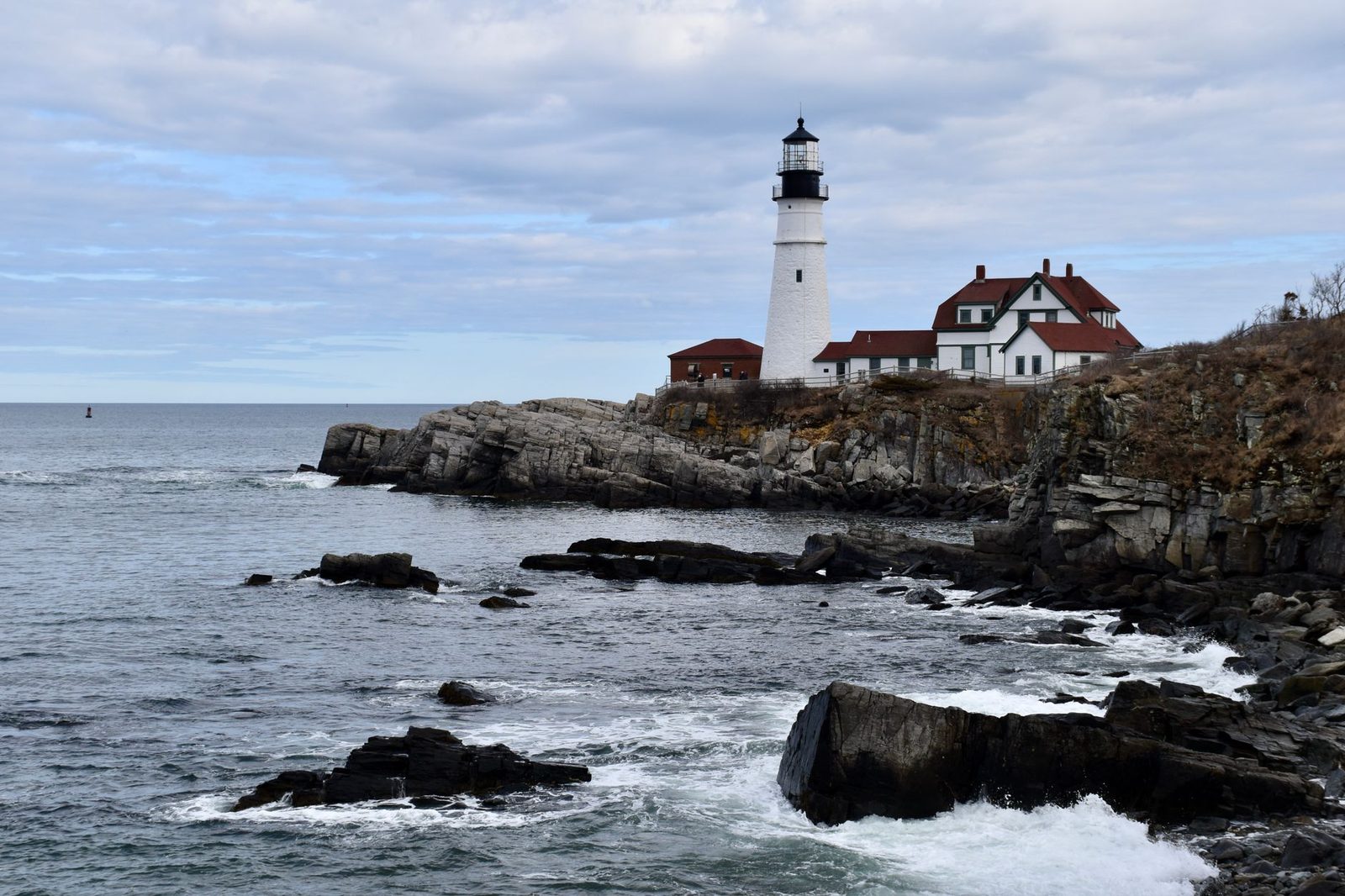 Portland Head Light in Maine overlooks a dramatic rocky coast and ocean under a cloudy sky, perfect for serene seascape